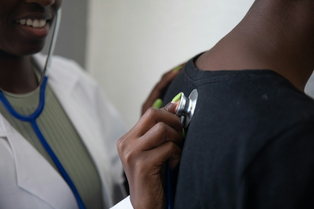 A clinician listening to a patient’s upper back with a stethoscope