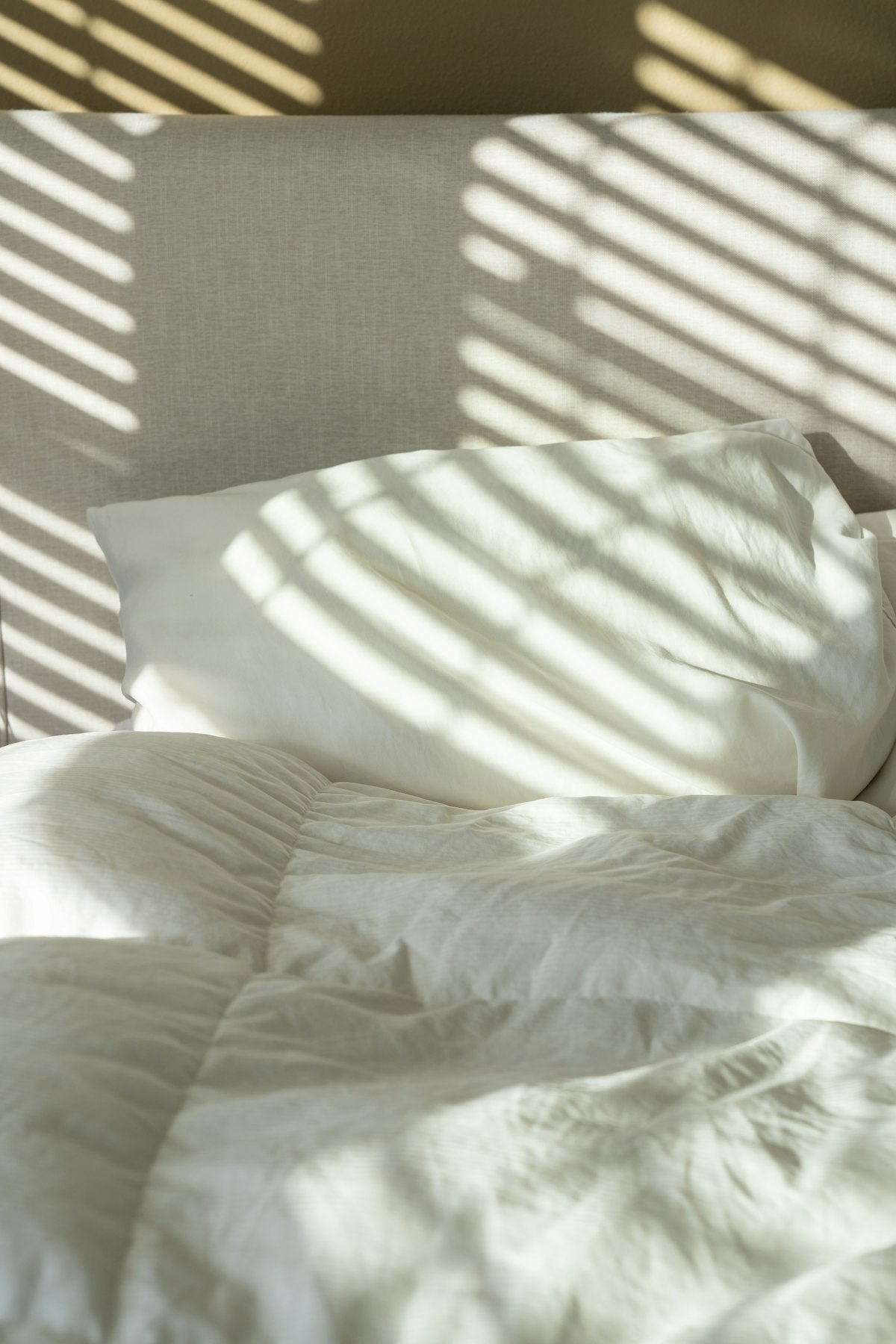 Soft daylight falling across white pillows and bed linen