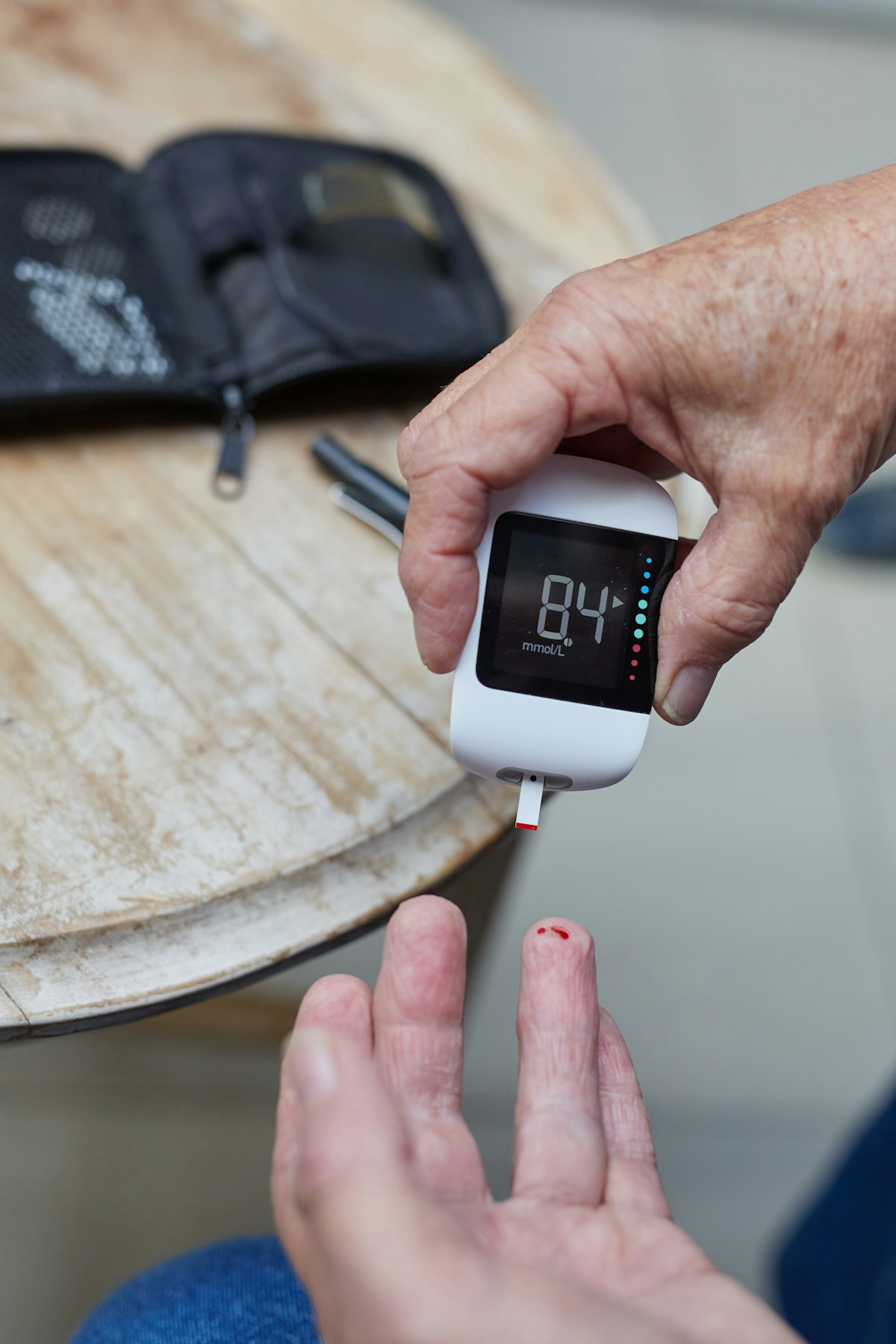A person checking a glucose meter beside a fingertip